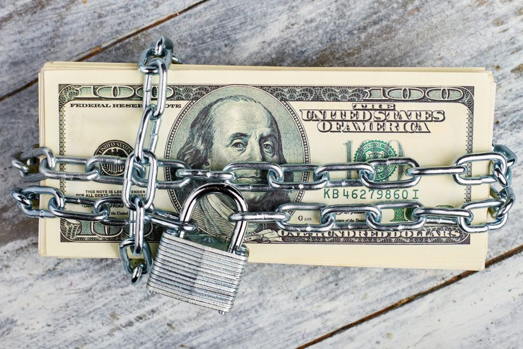 Locked dollars on wooden background.