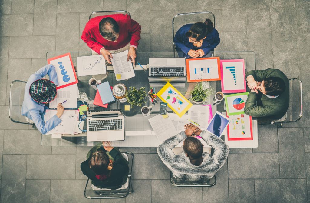 People sitting around a table at a meeting, aerial shot.