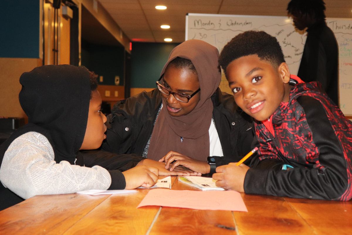 Two young boys with mentor working on homework