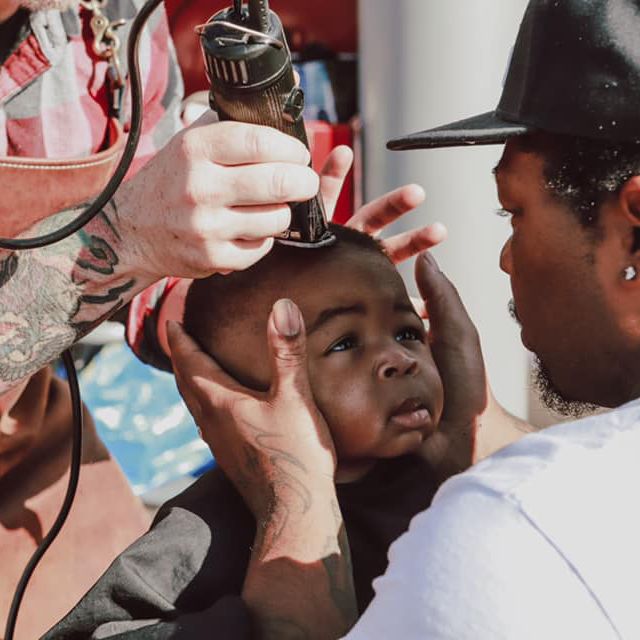 Steller Kindness Project giving a young child a haircut as a man cups the child's face