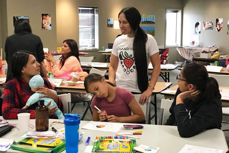 women talking at workshop while young girl colors