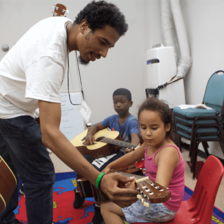 Andre Bronson, violin & early childhood instructor at Hopewell, teaches a student a chord on guitar.